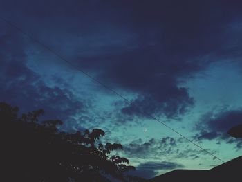 Low angle view of silhouette trees against dramatic sky