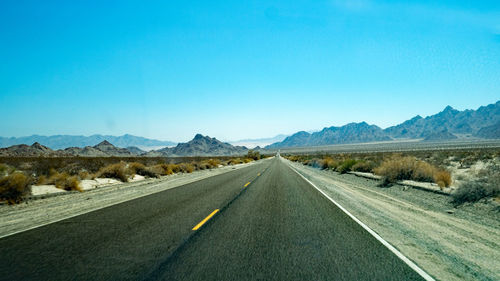 Road amidst landscape against clear blue sky