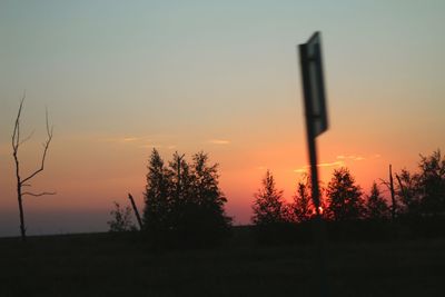 Silhouette trees on field against sky during sunset