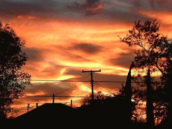 Silhouette of trees against cloudy sky at sunset