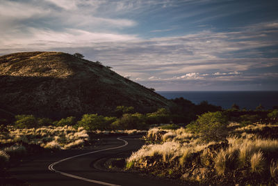 Road by mountains against sky