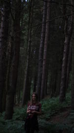 Girl standing on field against trees at forest