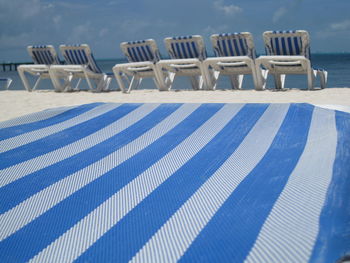 Close-up of deck chair at beach against sky