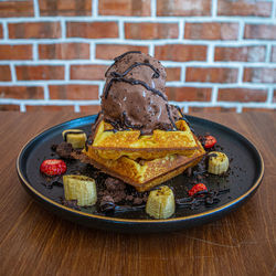 Close-up of dessert in plate on table against wall