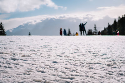 People on snow covered land against mountain and sky