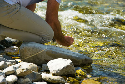 Low section of man with hands cupped by river 