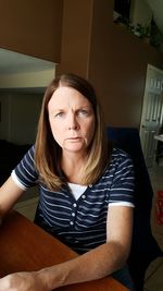 Portrait of beautiful woman sitting on table at home