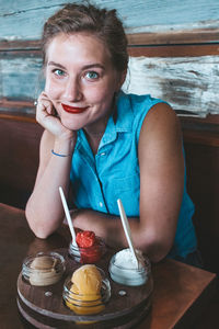 Portrait of smiling young woman with ice cream on table