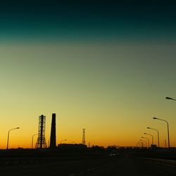 Silhouette of factory against sky during sunset