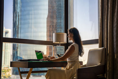 Rear view of woman using laptop at home