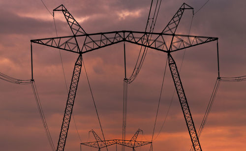 Low angle view of silhouette electricity pylon against sky