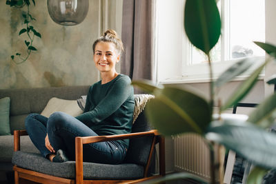 Portrait of smiling woman sitting on armchair at home