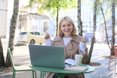 Young woman using laptop while sitting on chair