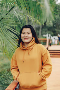 Portrait of young woman standing against plants