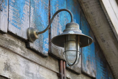 Low angle view of old metal lamp mounted on wall