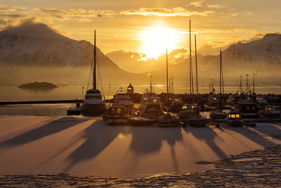 Boats moored at harbor against sky during winter
