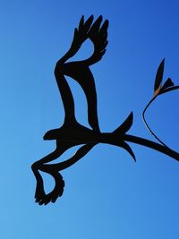 Low angle view of silhouette statue against blue sky