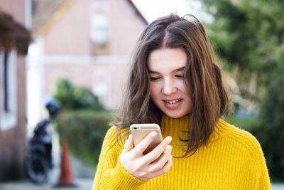 Portrait of smiling young woman using mobile phone outdoors