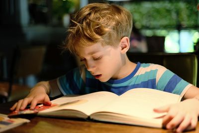 Close-up of boy with book on table