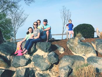 People sitting on rock against sky