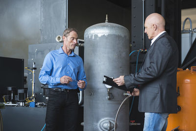 Two men looking at clipboard in factory