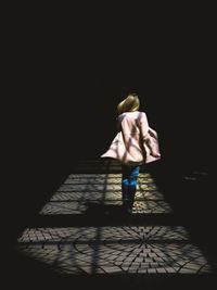 Rear view of young woman standing against black background