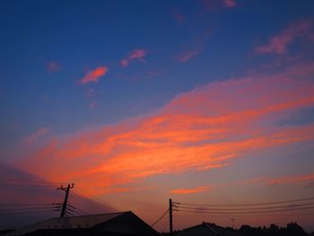 Low angle view of silhouette telephone pole against sky during sunset