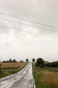 Road amidst field against sky