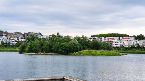 Scenic view of river by buildings against sky