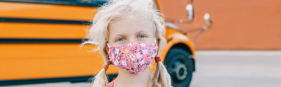 Portrait of cute girl wearing mask standing outdoors