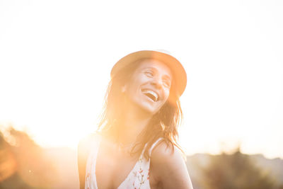 Cheerful woman looking away against sky during sunset