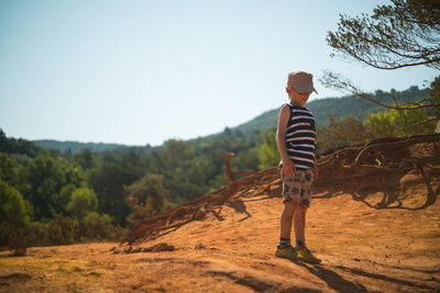 Full length of boy standing on land against sky