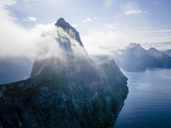 Scenic view of sea by mountains against sky