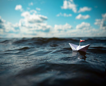 Close-up of paper floating on water against sky