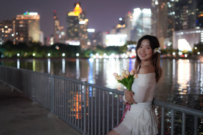 Portrait of young woman standing in city at night