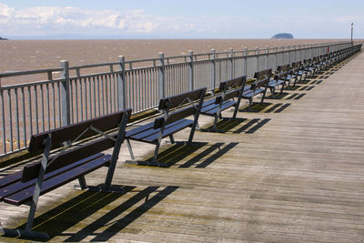 Row of railing by sea against sky