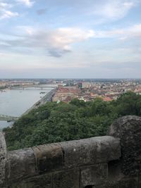 Scenic view of river by buildings against sky