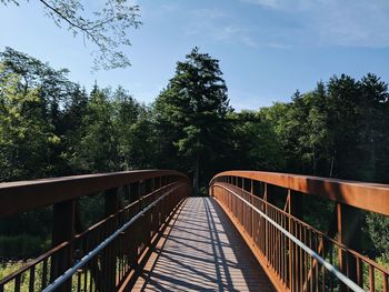 Footbridge amidst trees against sky