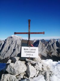 Low angle view of information sign on mountain against clear blue sky