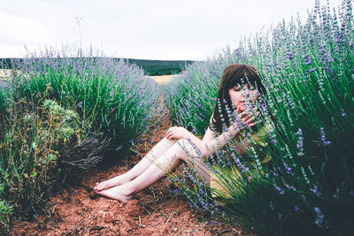 Young woman on field by flowering plants