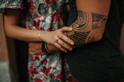 Close-up midsection of couple embracing while standing outdoors