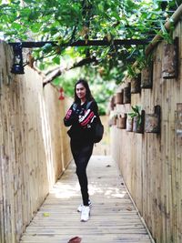 Full length portrait of young woman standing on footpath