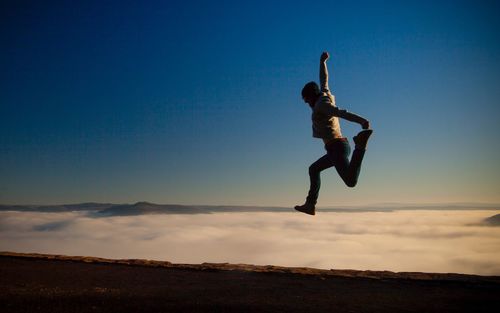 Silhouette man jumping against sky