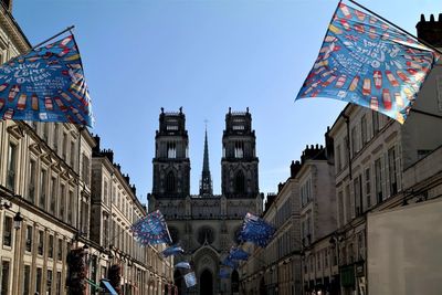 Low angle view of flags and buildings against sky