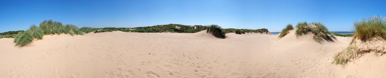 Panoramic view of beach against clear blue sky