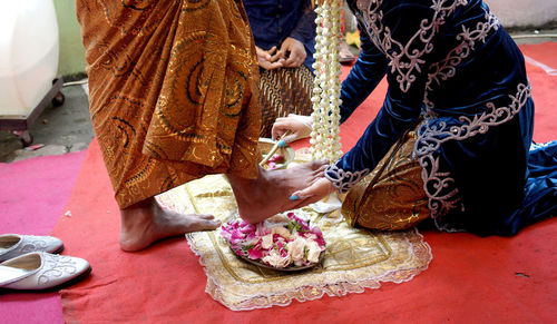 Low section of woman washes groom's feet