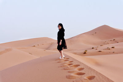 Full length of woman standing on sand dune