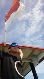 Low angle view of man flag against sky