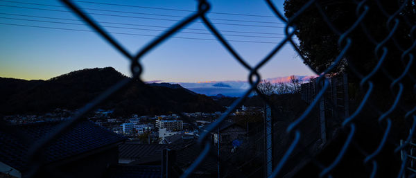 Panoramic view of city seen through chainlink fence