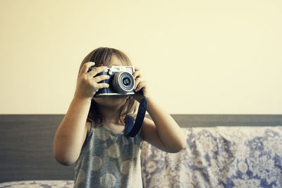 Girl photographing while sitting on bed at home